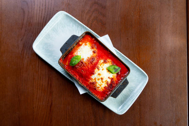 Hot juicy lasagna in casserole with basil leaves on top, served on the table in fine dining
