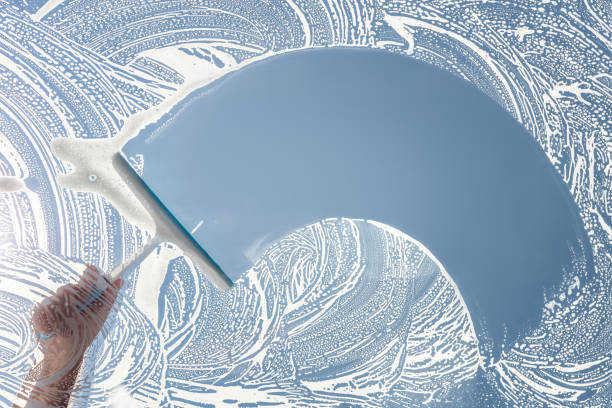 istock Window cleaner using a squeegee to wash and clean a window 2176099285