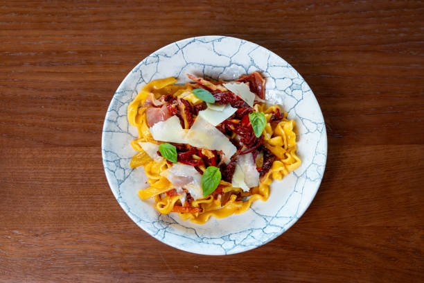 Tagliatelle pasta with ham and dried tomato, grana cheese and basil on top served in fine dining