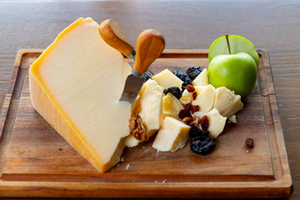 Hard cow's milk cheese served on wooden board with green apple, prunes and nuts in fine dining