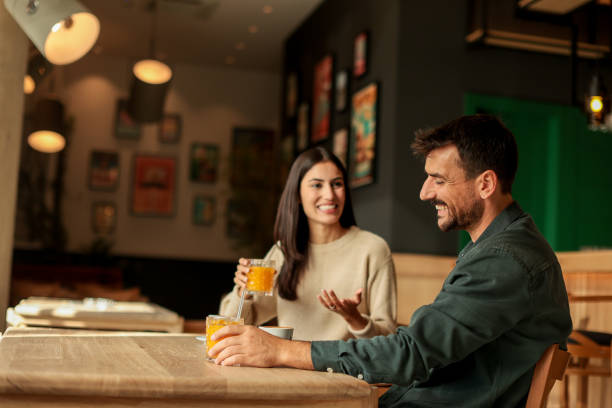 istock Couple enjoying at a cozy cafe with warm drinks and laughter in a vibrant, modern setting on a sunny afternoon 2176101444