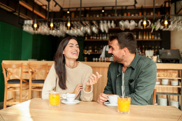 istock Couple enjoying at a cozy cafe with warm drinks and laughter in a vibrant, modern setting on a sunny afternoon 2176101455