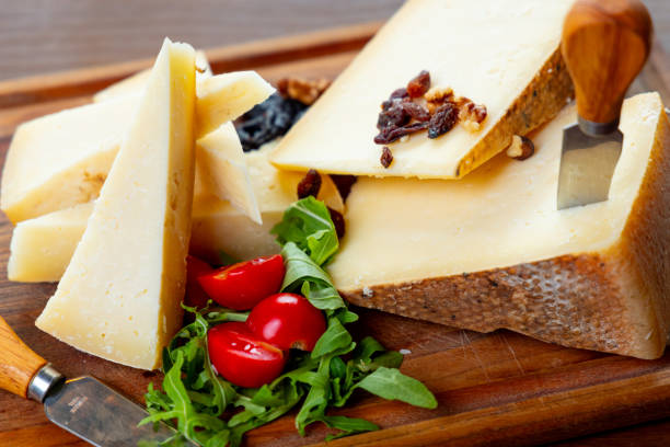 Hard cow's milk cheese served on wooden board with cherry tomato and basil in fine dining