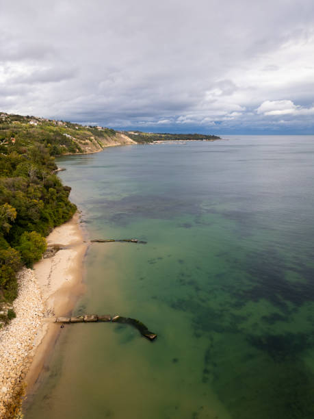 A serene coastal landscape with a sandy beach, lush green cliffs, and calm waters stretching into the horizon under a cloudy sky. Perfect for travel, nature, or coastal themes. Varna, Bulgaria