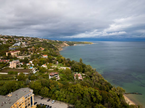 A serene coastal landscape with a sandy beach, lush green cliffs, and calm waters stretching into the horizon under a cloudy sky. Perfect for travel, nature, or coastal themes. Varna, Bulgaria