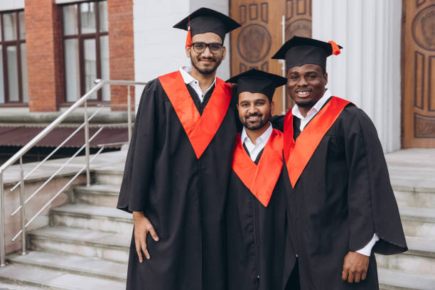 istock Group of Graduates Celebrating in Cap and Gown on University Steps Smiling Proudly 2176108564