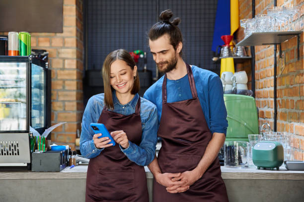 istock Young man and woman restaurant coffee shop workers using smartphone together 2176110839