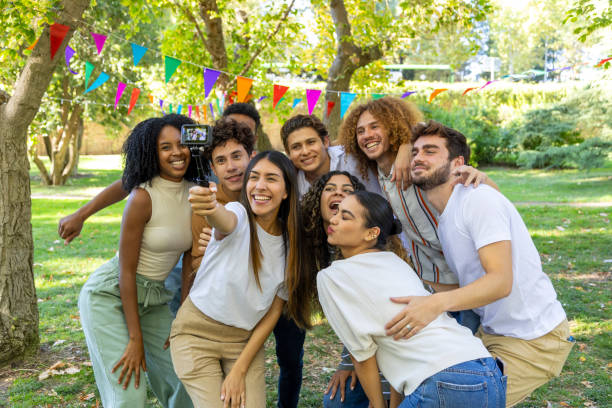 istock Group of friends taking selfie in park using selfie stick 2176111564