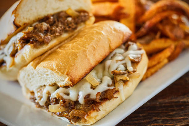 Aspirational shot of a fully loaded Philly cheese steak sandwich with peppers, onions, mushrooms, and cheese, isolated on white with shadow.