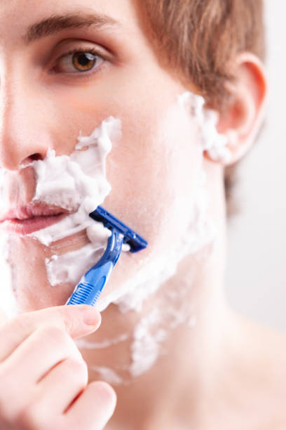 istock Young man carefully shaving face with razor in bathroom 2176118662