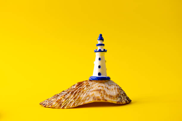 Close up of white miniature lighthouse on a seashell, sea and travel concept