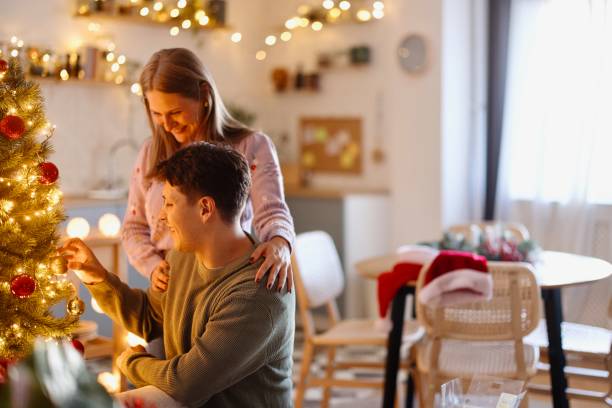 istock Smiling boyfriend and girlfriend decorating Christmas tree 2176128021