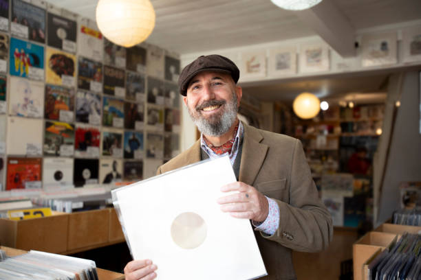Mature man holding a record in a vinyl in a record shop