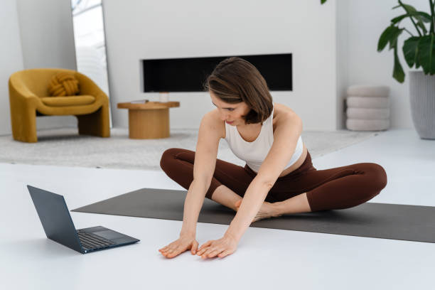 istock Young woman doing exercise at home and watching online classes using laptop. Copy space. 2176128732
