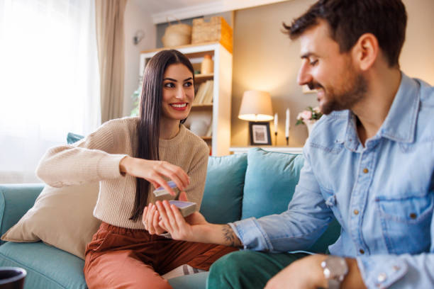 istock Couple playing card games while relaxing at home, woman cutting card deck 2176128984