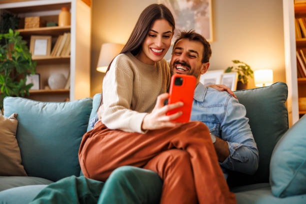 istock Couple in love hugging and using smart phone at home 2176129264