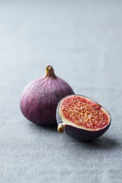 istock Ripe fresh organic fig fruit with a sliced piece on a grey background with a soft light, simple minimalistic shot 2176129427