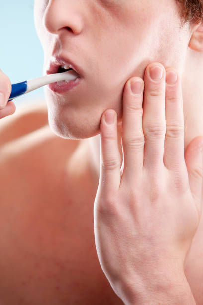 istock Young man concentrating while brushing his teeth in bathroom 2176134759
