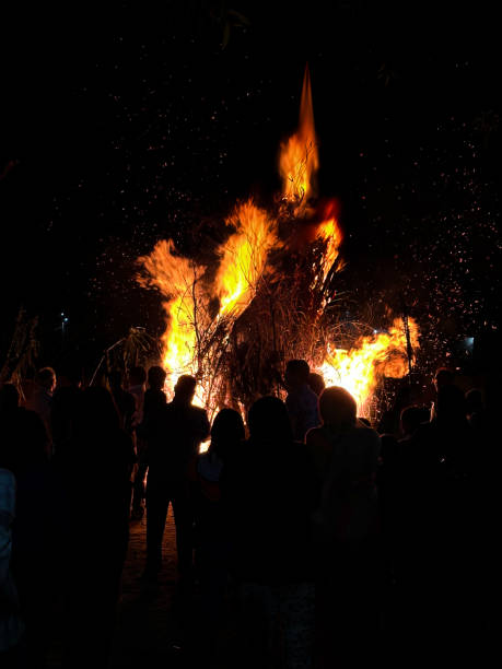 istock Image of silhouetted figures backlit by roaring bonfire, sparks flying in dark night sky, crowds celebrating Guy Fawkes bonfire night 2176135060