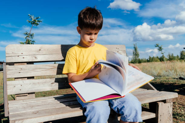 istock A child reads a book sitting on a bench in nature during the day 2176135879