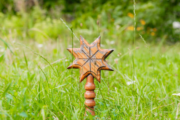 wooden talisman pagan idol carved art crafted hand made object religion pattern center of composition outdoor grass land blurred natural background space