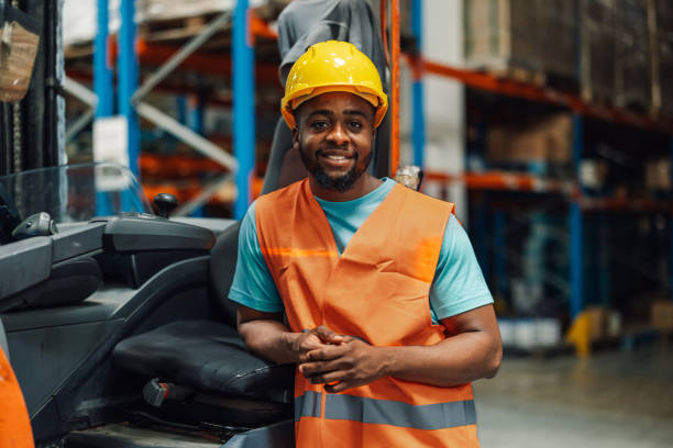 istock African american male warehouse worker in hard hat leaning on forklift machine 2176149605