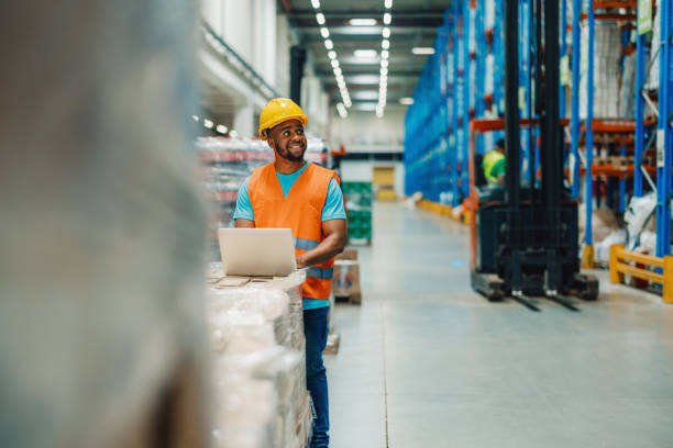istock African American warehouse worker checking inventory levels on a laptop device. 2176149608