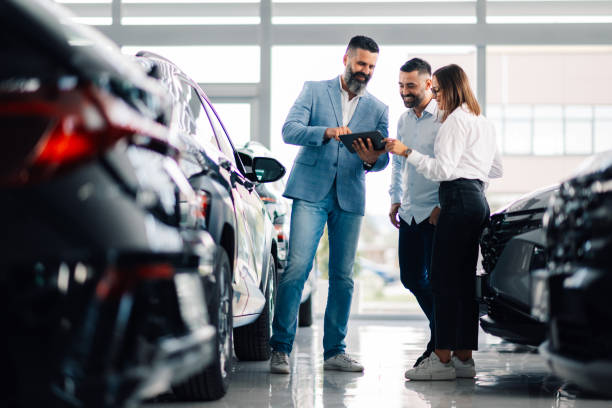 istock Car dealership trio assessing vehicle options with tablet view 2176149686