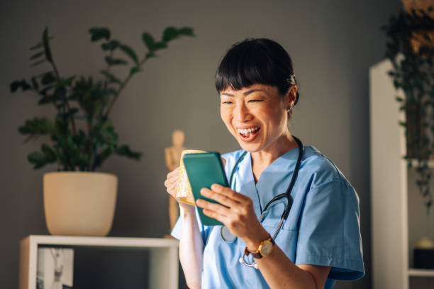 istock Asian female nurse laughing at her phone while holding a coffee mug 2176149846