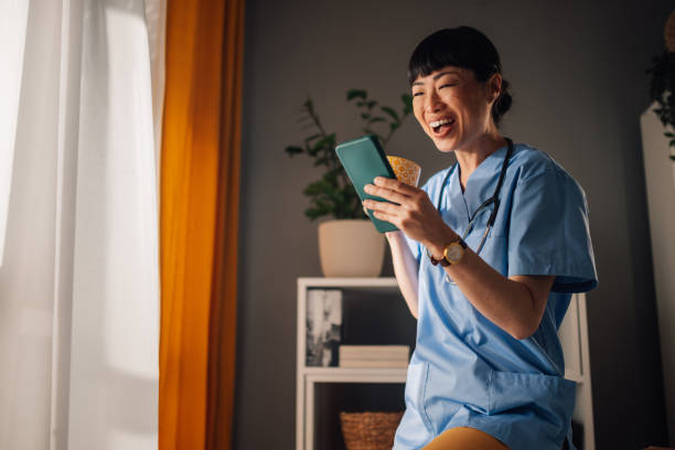 istock Asian medical professional standing by window with smartphone and mug 2176149867