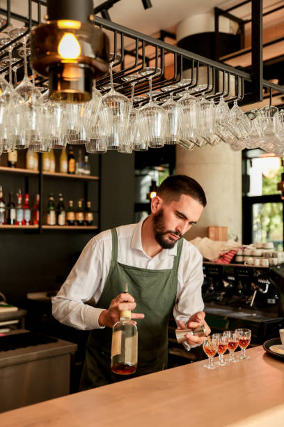 istock Skilled bartender artfully pouring colorful cocktails in a lively bar setting during the evening rush 2176152043