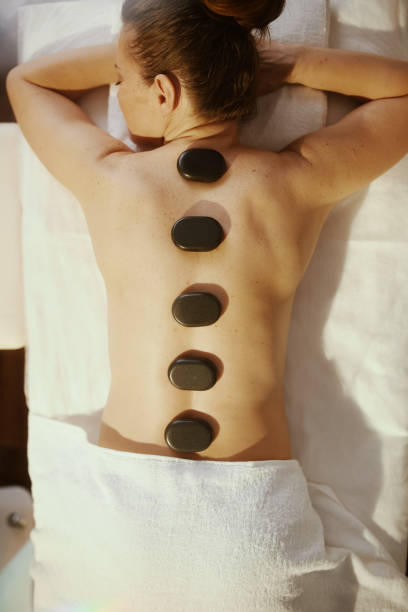 istock woman having hot stone massage and laying on massage table 2176154268