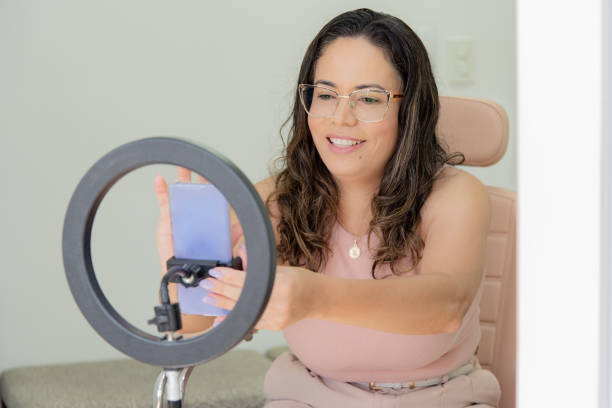 istock woman sitting with cell phone and tripod for recording 2176154440