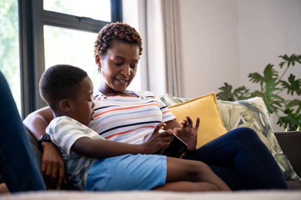 istock Mother sitting with her son playing on a digital tablet 2176154569