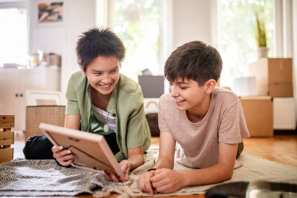 istock Two friends smiling and looking at a picture frame. 2176156839