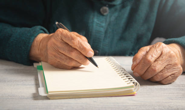 istock Caucasian elderly woman writes in notepad. 2176157374
