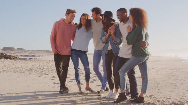istock Group Of Casually Dressed Friends Having Fun Standing On Winter Beach Together 2176171194