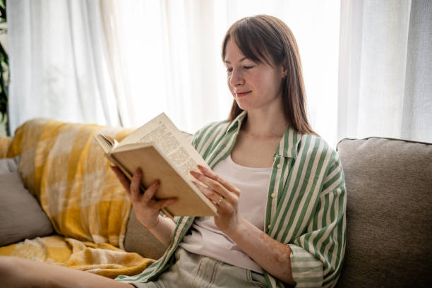 istock Woman focused on a book while seated on couch. 2176172774