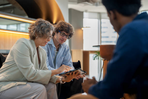 istock Multiracial group of product developers meeting on a sofa in a modern coworking space, using a digital tablet to analyze data. Collaborative teamwork and problem-solving, emphasizing communication, innovation, and employee engagement in a creative busines 2176173688