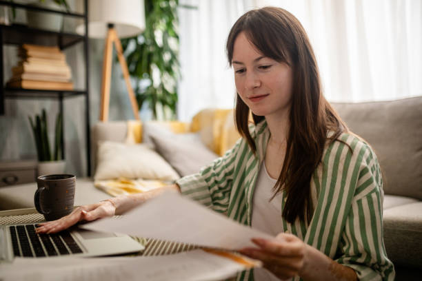 istock Focused woman working on laptop and handling papers. 2176176668