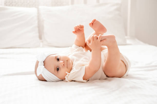 istock Cute newborn baby girl playing with her legs lying on her back o 2176182314