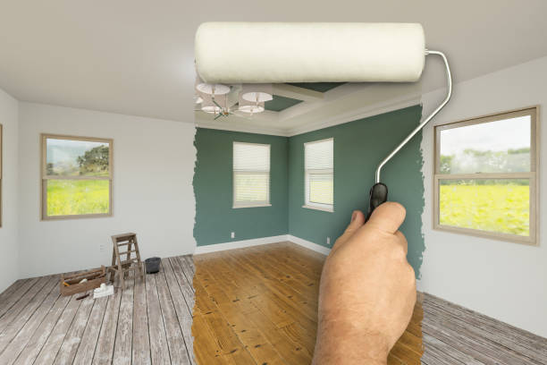 istock Before and After of Man Using A Paint Roller to Reveal Newly Remodeled Room with Fresh Green Paint, Coffered Ceiling and New Floors. 2176183021