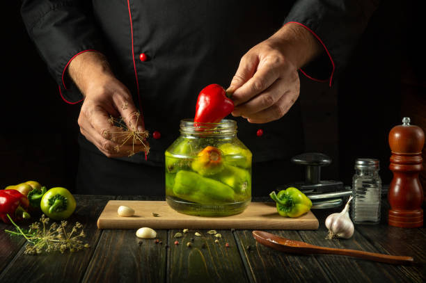 istock Chef manually fills a jar red with bell pepper before preserving them with spices in a jar. The concept of pickling delicious bell peppers with spices and garlic 2176185479
