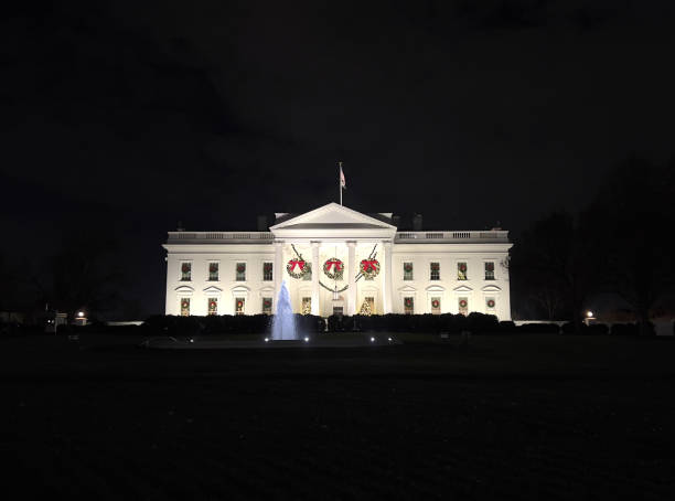 The White House, where the President of the United States lives, is lit up in the dark and decorated with Christmas decorations.