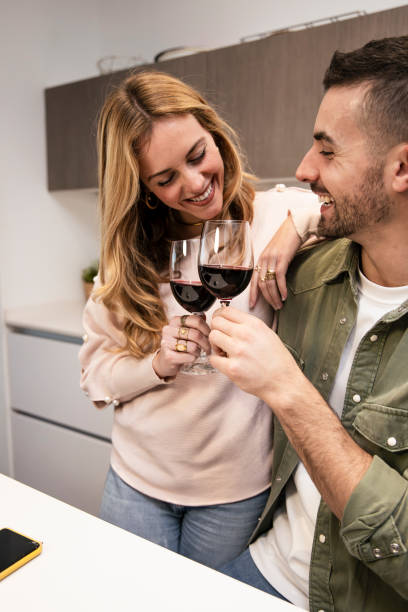 istock Affectionate joyful couple celebrating toasting with wine in kitchen. Happy smiling man and woman drinking with glasses in home. 2176187945