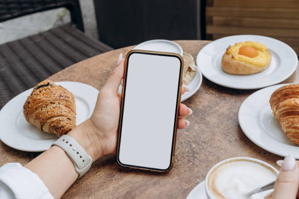 istock Mockup woman's hand holding using smart phone with white blank screen POV at coffee shop, mobile app design and advertising, online marketing 2176189453