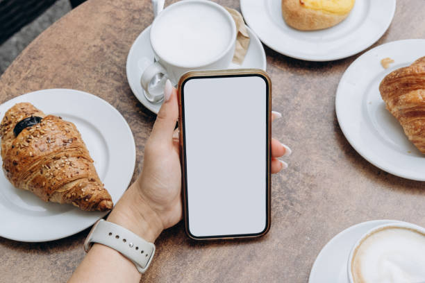 istock Mockup woman's hand holding using smart phone with white blank screen POV at coffee shop, mobile app design and advertising, online marketing 2176189464