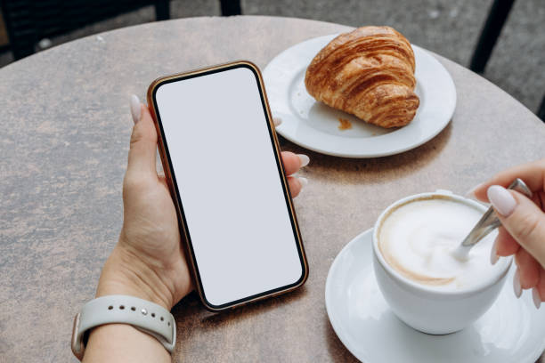 istock Mockup woman's hand holding using smart phone with white blank screen POV at coffee shop, mobile app design and advertising, online marketing 2176189476