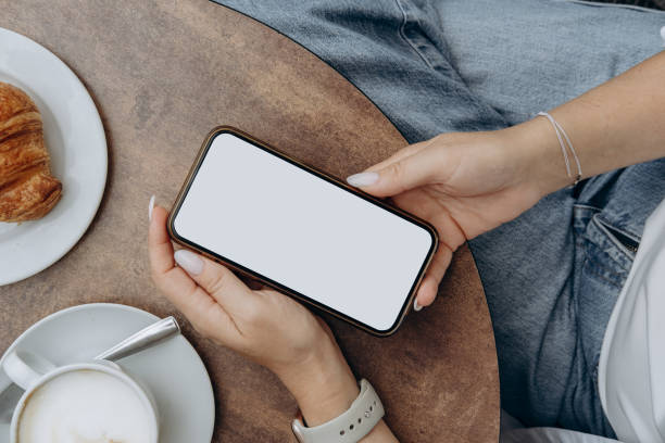 istock Mockup woman's hand holding using smart phone with white blank screen POV at coffee shop, mobile app design and advertising, online marketing 2176189486