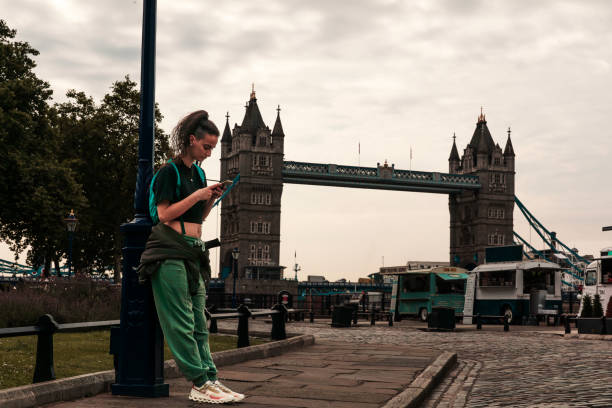Young woman checking her phone with London Bridge in background